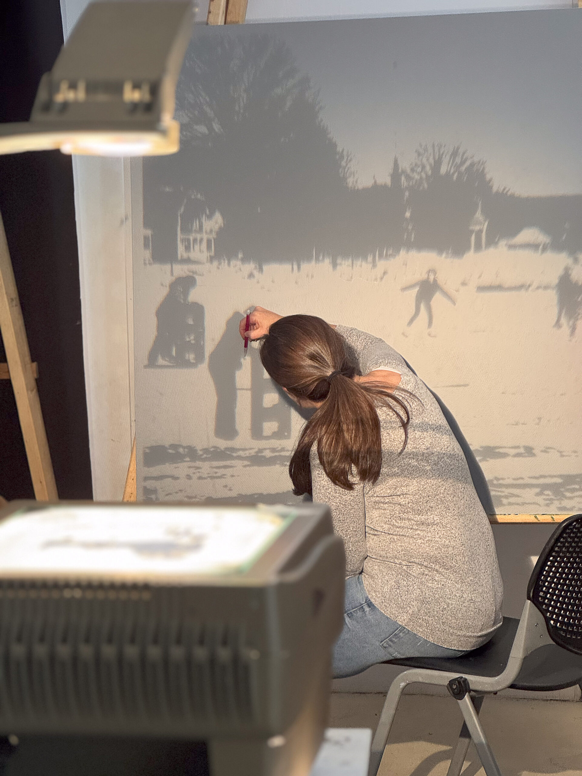 4 - Mary Georgilas uses a projector to trace her mural design depicting skating on Newport’s Town Common on her 4x4 panel.